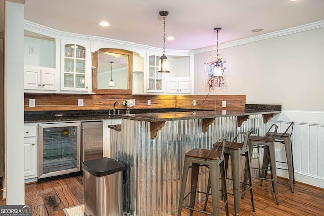 395 Grove Ridge Dr, Loganville, GA 30052 - bar area featuring wine cooler, dark wood-style floors, decorative light fixtures, ornamental molding, and wainscoting