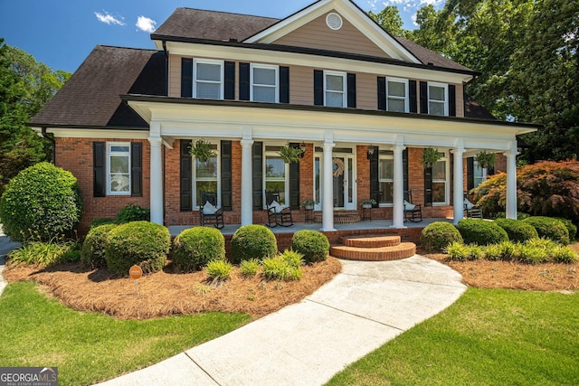 395 Grove Ridge Dr, Loganville, GA 30052 - view of front of house with brick siding, a porch, a front lawn, and roof with shingles