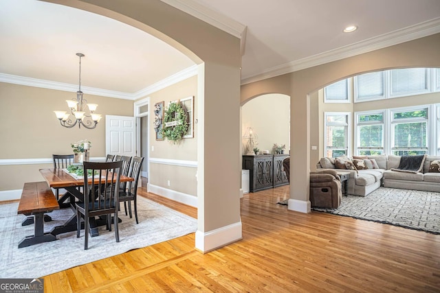 395 Grove Ridge Dr, Loganville, GA 30052 - dining area featuring arched walkways, light wood finished floors, ornamental molding, and a chandelier