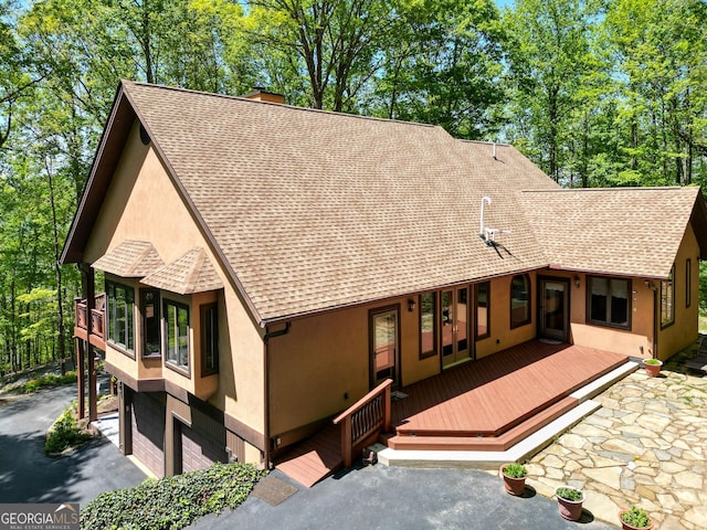1289 Rainwater Trl, Tiger, GA 30576 - view of front of house with roof with shingles, stucco siding, a chimney, an attached garage, and a wooden deck