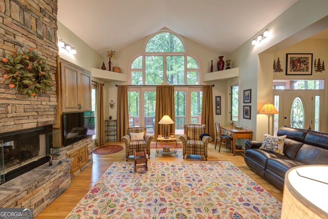 1289 Rainwater Trl, Tiger, GA 30576 - living room featuring light wood-style flooring, a stone fireplace, and high vaulted ceiling