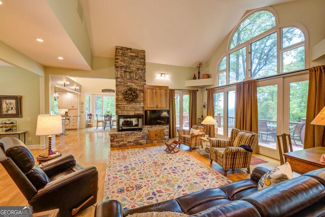 1289 Rainwater Trl, Tiger, GA 30576 - living area featuring light wood-type flooring, high vaulted ceiling, plenty of natural light, a stone fireplace, and recessed lighting