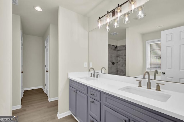 6341 Stewart Ridge Walk, Buford, GA 30518 - bathroom featuring double vanity, tiled shower, wood finished floors, baseboards, and recessed lighting