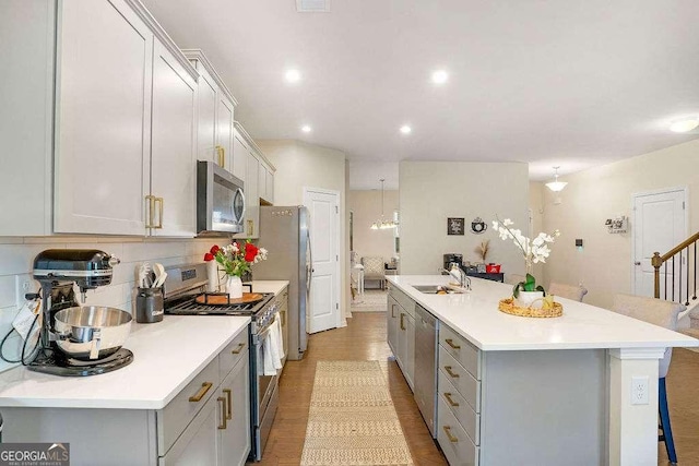 105 Paulowina Cir, Mcdonough, GA 30253 - kitchen with stainless steel appliances, gray cabinetry, a center island with sink, light countertops, and a kitchen breakfast bar