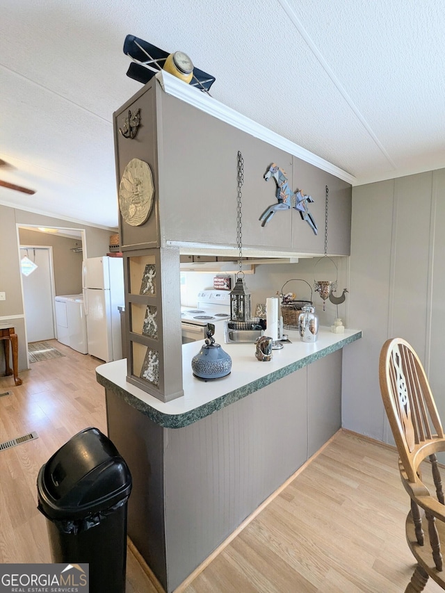 1096 Tesnatee Gap Valley Rd, Cleveland, GA 30528 - kitchen featuring white appliances, washing machine and dryer, light wood-style floors, and a peninsula