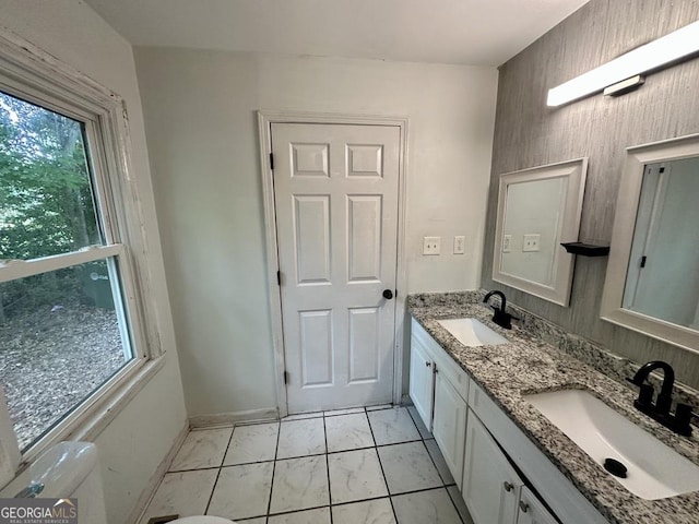 1681 Stanton Rd SW, Atlanta, GA 30311 - bathroom featuring toilet, marble look tiles, double vanity, and baseboards