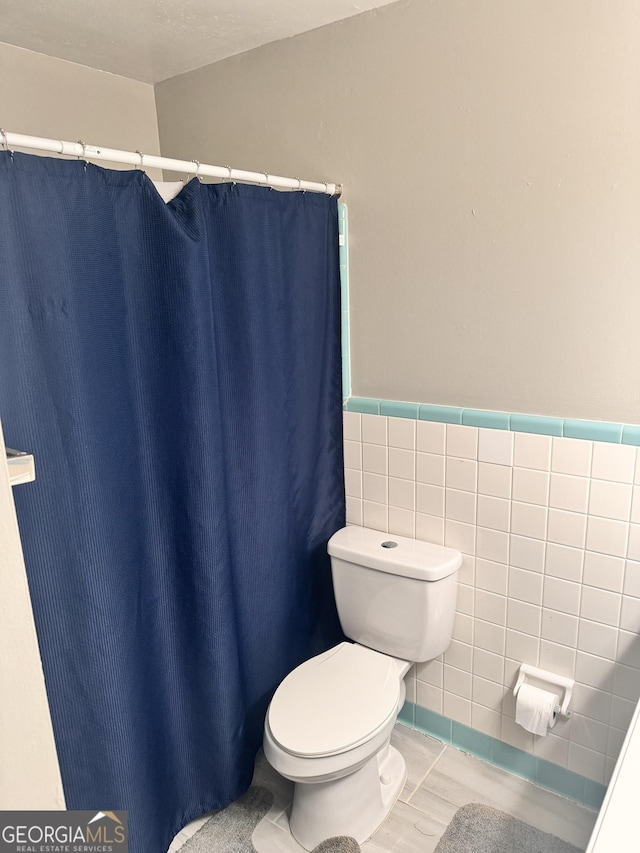 206 Audubon Way, Warner Robins, GA 31088 - bathroom featuring toilet, tile walls, a shower with curtain, wainscoting, and wood finished floors