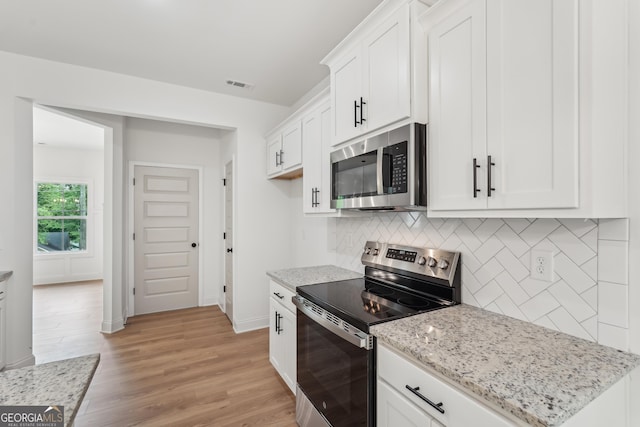 2279 Lakeview Pkwy, Villa Rica, GA 30180 - kitchen with stainless steel appliances, backsplash, light stone countertops, white cabinets, and light wood-type flooring