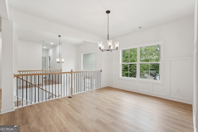 2279 Lakeview Pkwy, Villa Rica, GA 30180 - spare room featuring a chandelier, a decorative wall, wood finished floors, and a wainscoted wall