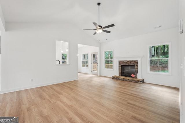 2279 Lakeview Pkwy, Villa Rica, GA 30180 - unfurnished living room featuring a stone fireplace, a ceiling fan, light wood finished floors, vaulted ceiling, and baseboards