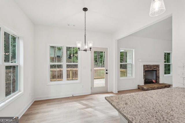2279 Lakeview Pkwy, Villa Rica, GA 30180 - unfurnished dining area with plenty of natural light, light wood-style floors, a chandelier, and a stone fireplace