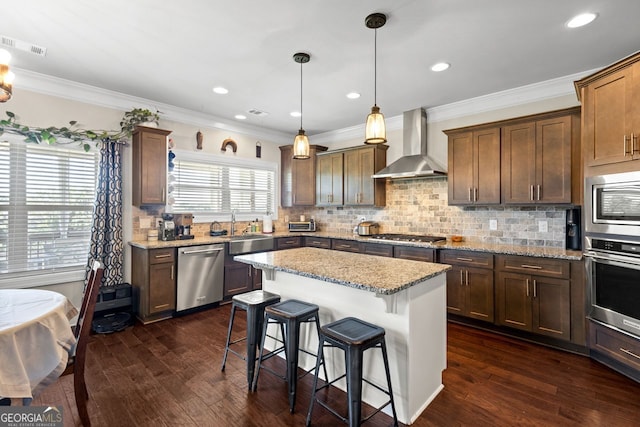 1858 Switchgrass Dr, Statham, GA 30666 - kitchen with wall chimney exhaust hood, stainless steel appliances, a sink, a breakfast bar, and ornamental molding
