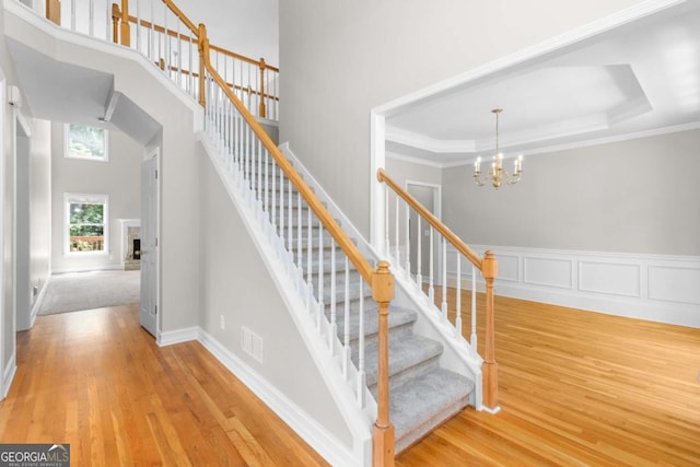85 Arabian Ave, Alpharetta, GA 30004 - stairs with wood finished floors, a chandelier, a high ceiling, crown molding, and a fireplace