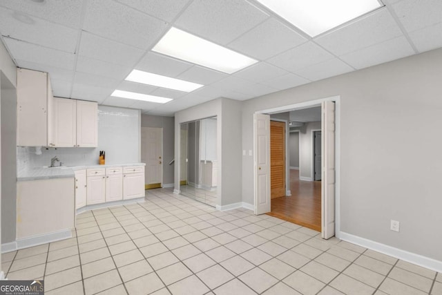 85 Arabian Ave, Alpharetta, GA 30004 - kitchen with light countertops, a paneled ceiling, white cabinets, baseboards, and light tile patterned flooring