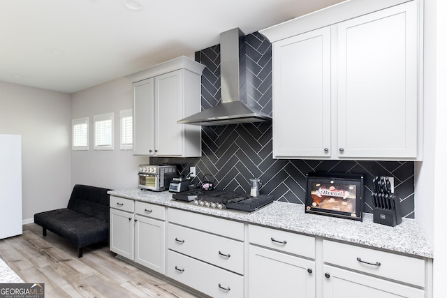 646 Mccarley Downs Dr, Bonaire, GA 31005 - kitchen with wall chimney exhaust hood, stainless steel gas cooktop, tasteful backsplash, light wood-style floors, and white cabinets