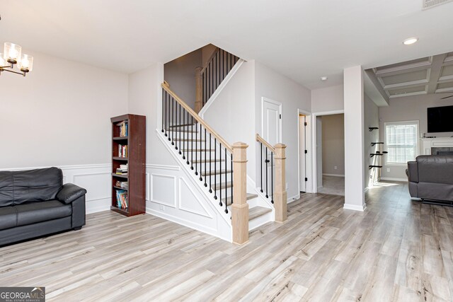 646 Mccarley Downs Dr, Bonaire, GA 31005 - living area featuring stairs, wood finished floors, a chandelier, a wainscoted wall, and a decorative wall