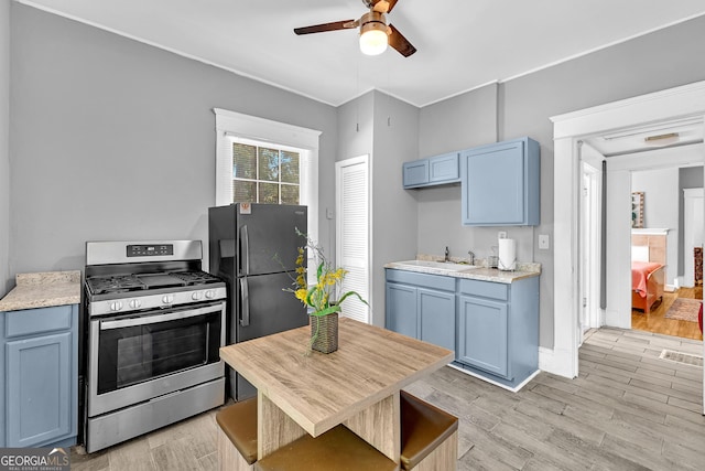 1021 Oak St SW, Atlanta, GA 30310 - kitchen featuring stainless steel range with gas cooktop, a ceiling fan, blue cabinets, freestanding refrigerator, and a sink