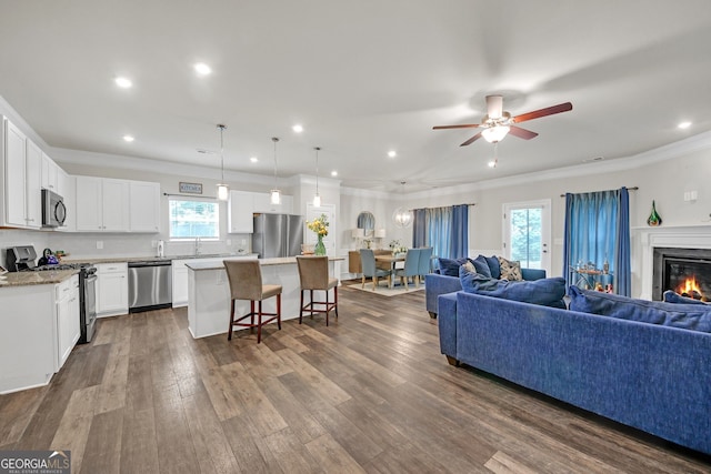 1431 Beckett Dr, Hampton, GA 30228 - living area featuring crown molding, ceiling fan, a glass covered fireplace, dark wood-type flooring, and recessed lighting