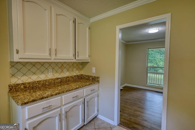 1226 Hull Rd, Athens, GA 30601 - kitchen with a textured ceiling, white cabinetry, backsplash, crown molding, and dark stone countertops