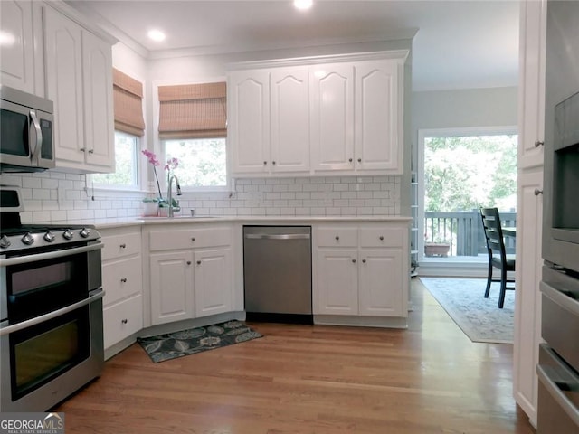 21 Devin Ln, Euharlee, GA 30145 - kitchen with appliances with stainless steel finishes, white cabinetry, light countertops, light wood finished floors, and decorative backsplash