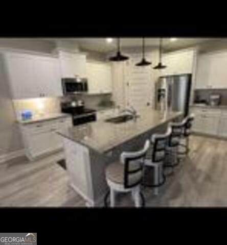 406 Clifton Rd, Perry, GA 31069 - kitchen featuring stainless steel appliances, white cabinets, a kitchen island, a sink, and light countertops