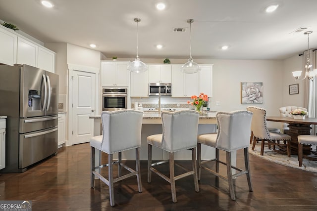 383 Crestbrook Ln, Dallas, GA 30157 - kitchen featuring stainless steel appliances, a breakfast bar area, white cabinets, dark wood-style flooring, and a center island with sink