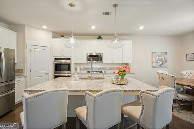 383 Crestbrook Ln, Dallas, GA 30157 - kitchen with stainless steel appliances, tasteful backsplash, light stone counters, a kitchen island with sink, and recessed lighting