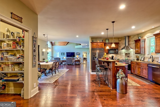 421 Hickory Nut Mountain Rd, Tallulah Falls, GA 30573 - kitchen with stainless steel appliances, wall chimney exhaust hood, open floor plan, a breakfast bar, and pendant lighting