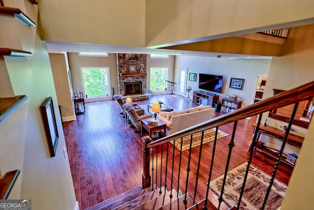 421 Hickory Nut Mountain Rd, Tallulah Falls, GA 30573 - stairway featuring a stone fireplace, a towering ceiling, and hardwood / wood-style flooring