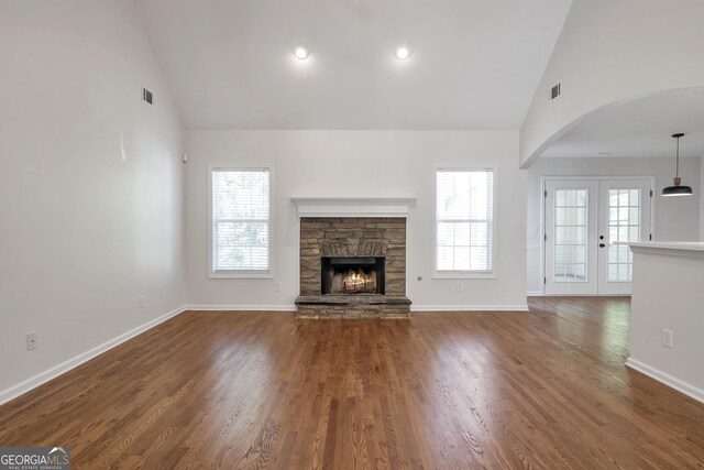 5523 River Valley Way, Flowery Branch, GA 30542 - unfurnished living room featuring arched walkways, high vaulted ceiling, a stone fireplace, baseboards, and wood finished floors