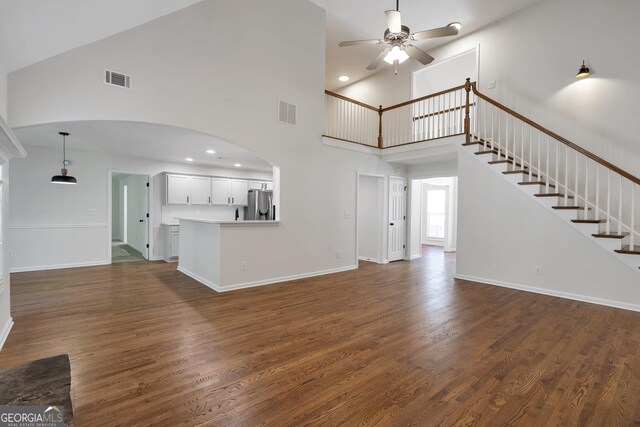5523 River Valley Way, Flowery Branch, GA 30542 - unfurnished living room featuring a ceiling fan, arched walkways, high vaulted ceiling, dark wood finished floors, and baseboards