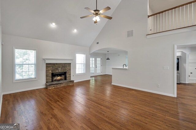 5523 River Valley Way, Flowery Branch, GA 30542 - unfurnished living room featuring high vaulted ceiling, a ceiling fan, arched walkways, a stone fireplace, and baseboards