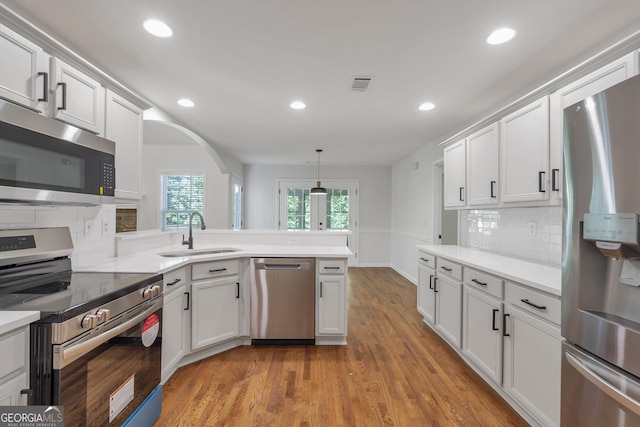 5523 River Valley Way, Flowery Branch, GA 30542 - kitchen with stainless steel appliances, a sink, arched walkways, backsplash, and light wood-style floors