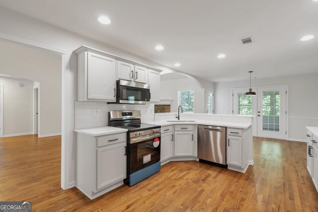 5523 River Valley Way, Flowery Branch, GA 30542 - kitchen featuring stainless steel appliances, a sink, arched walkways, a peninsula, and light countertops