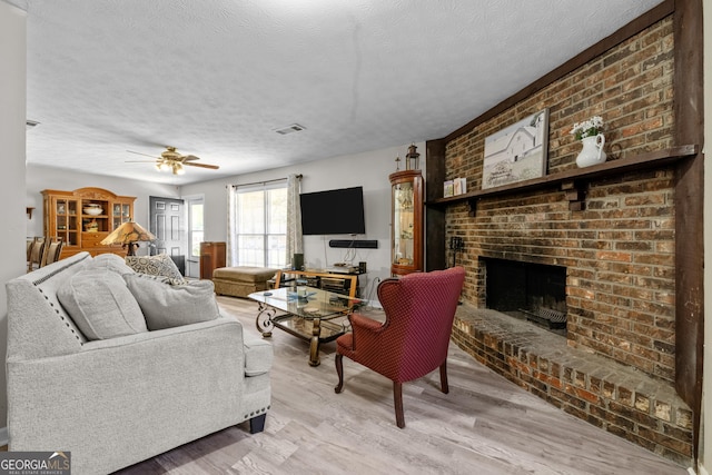 1322 Melford Dr, Columbus, GA 31907 - living room with a brick fireplace, a textured ceiling, light wood finished floors, and ceiling fan