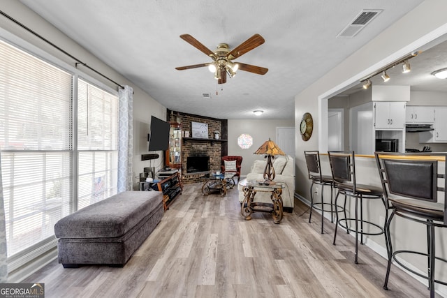 1322 Melford Dr, Columbus, GA 31907 - living area with a fireplace, plenty of natural light, ceiling fan, light wood-style flooring, and a textured ceiling