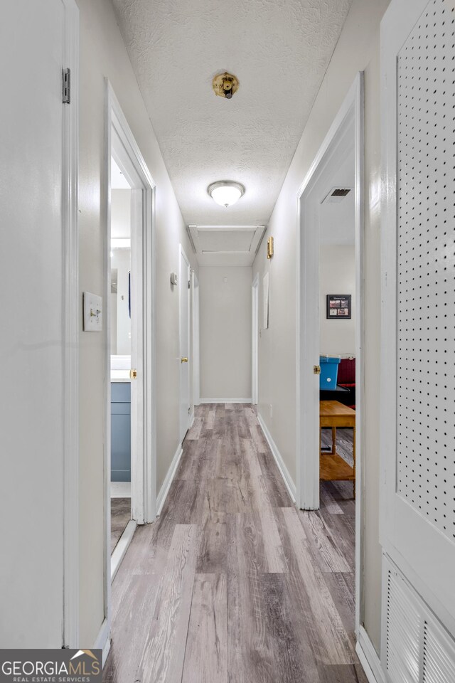 1322 Melford Dr, Columbus, GA 31907 - corridor with wood finished floors, a textured ceiling, baseboards, and attic access