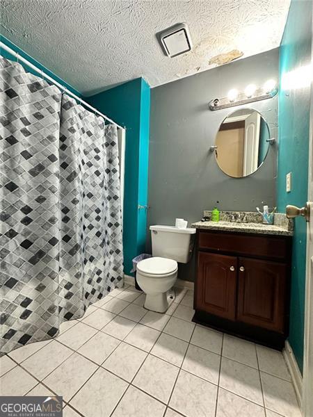 2816 Quinbery Dr, Snellville, GA 30039 - bathroom featuring vanity, toilet, tile patterned flooring, a textured ceiling, and a shower with curtain