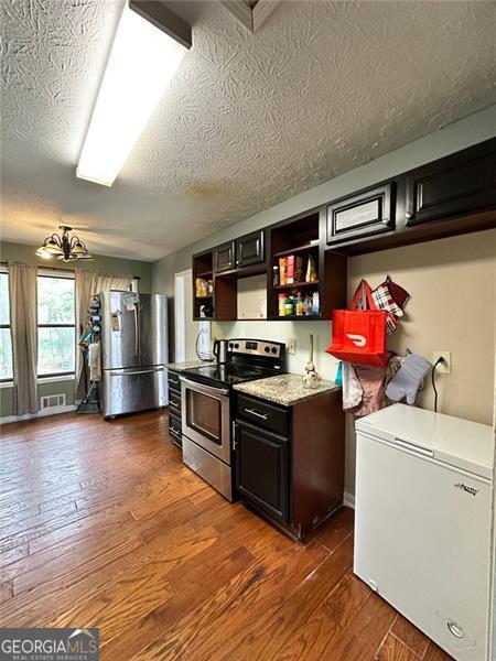 2816 Quinbery Dr, Snellville, GA 30039 - kitchen featuring stainless steel appliances, open shelves, dark wood finished floors, a textured ceiling, and light countertops