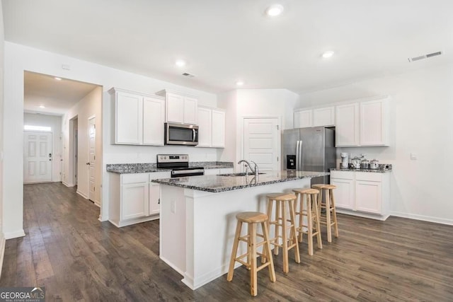 115 Taylor Woods Ct, Bonaire, GA 31005 - kitchen featuring stainless steel appliances, dark wood-style flooring, a sink, white cabinetry, and a breakfast bar area