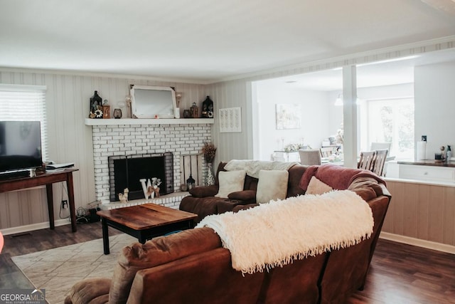175 Briarwood Cir, Americus, GA 31709 - living area featuring dark wood-style flooring, a brick fireplace, crown molding, and wood walls