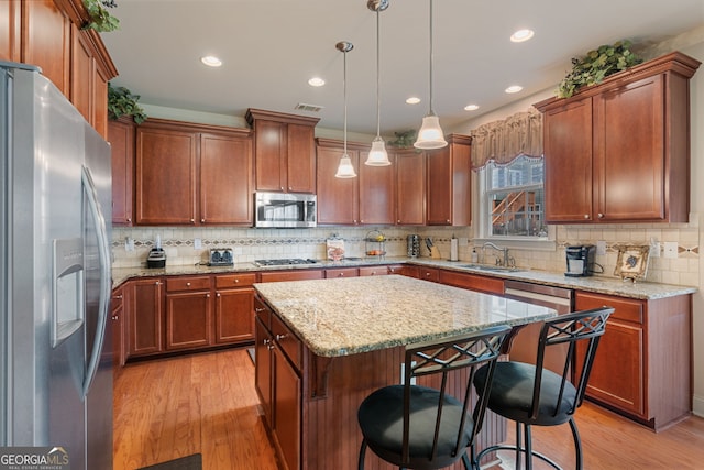 3476 Bridge Walk Dr, Lawrenceville, GA 30044 - kitchen with stainless steel appliances, a sink, a breakfast bar area, light wood-type flooring, and backsplash