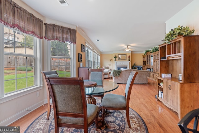 3476 Bridge Walk Dr, Lawrenceville, GA 30044 - dining space featuring healthy amount of natural light, a fireplace, ceiling fan, light wood-style flooring, and crown molding