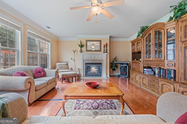 3476 Bridge Walk Dr, Lawrenceville, GA 30044 - living room with crown molding, wood finished floors, a glass covered fireplace, and a ceiling fan