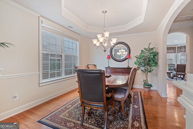 3476 Bridge Walk Dr, Lawrenceville, GA 30044 - dining space with arched walkways, light wood finished floors, a chandelier, a tray ceiling, and crown molding