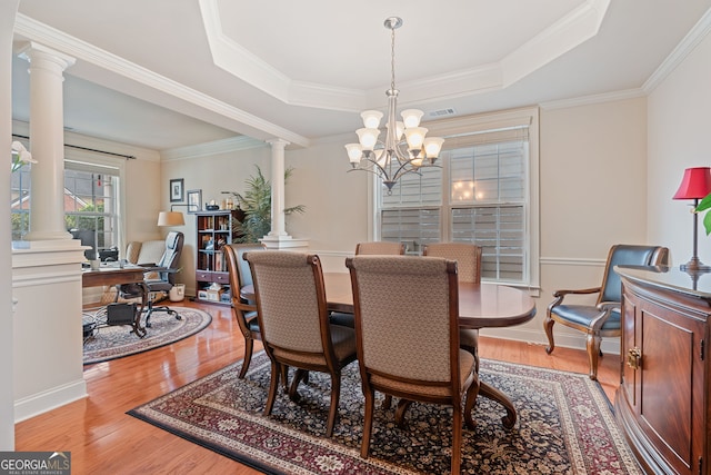 3476 Bridge Walk Dr, Lawrenceville, GA 30044 - dining room featuring ornate columns, a raised ceiling, a chandelier, light wood finished floors, and ornamental molding