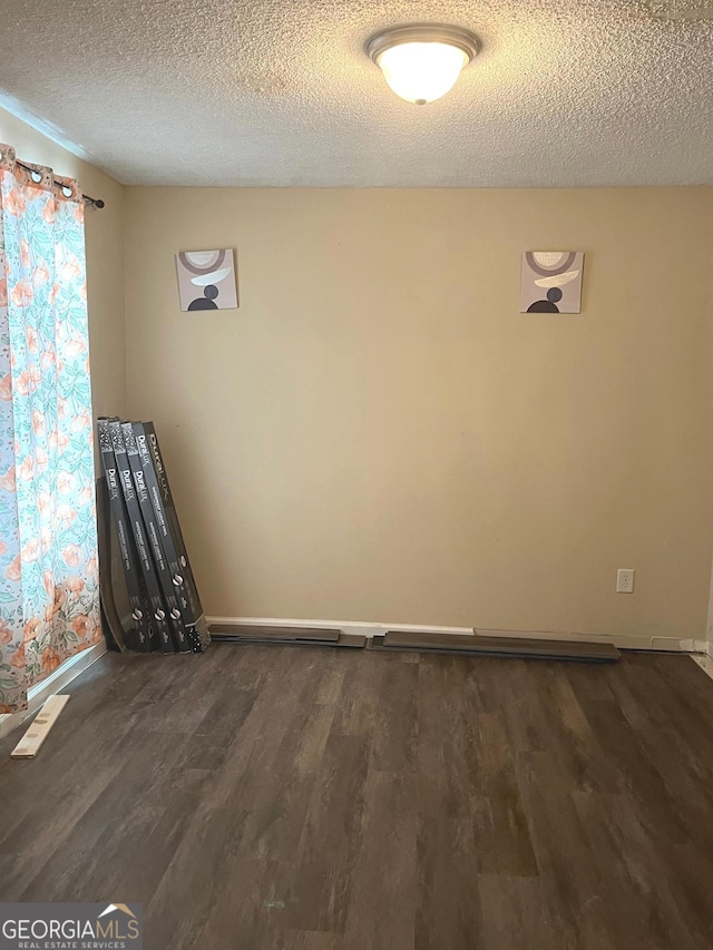 11657 Flemming Ct, Hampton, GA 30228 - unfurnished room with dark wood-type flooring, a textured ceiling, and baseboards