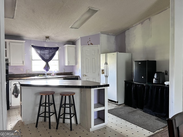 542 Southern Pines Rd, Dublin, GA 31021 - kitchen with white fridge with ice dispenser, tile countertops, white cabinetry, light floors, and a textured ceiling