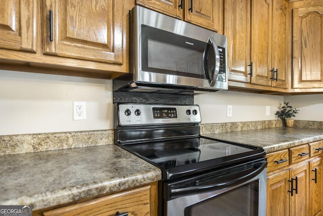 4407 Jones Rd, Macon, GA 31216 - kitchen with stainless steel appliances, brown cabinetry, and dark countertops