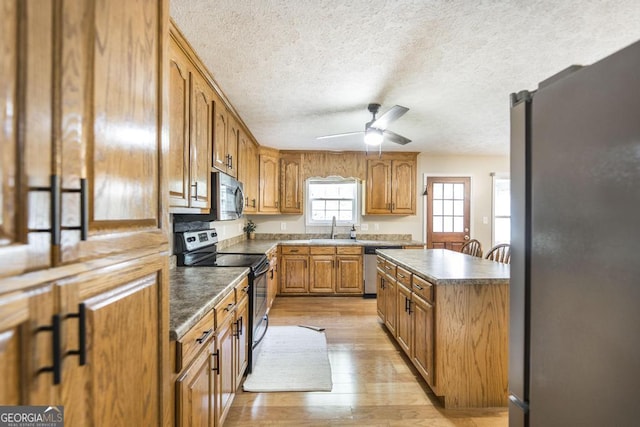 4407 Jones Rd, Macon, GA 31216 - kitchen with stainless steel appliances, a sink, light wood-type flooring, a ceiling fan, and brown cabinetry
